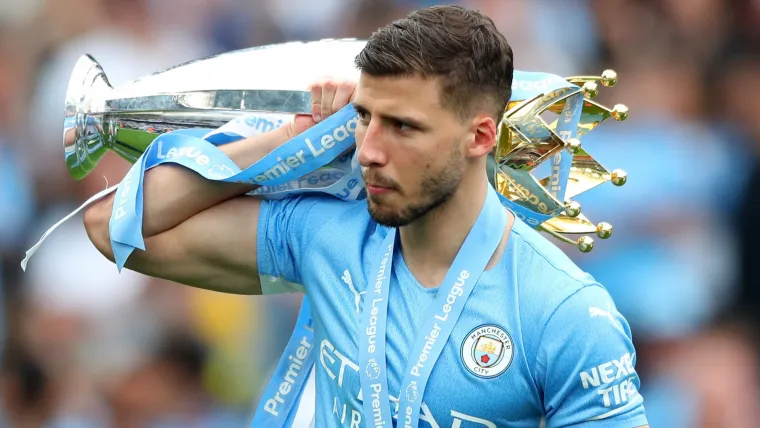 Ruben Dias carries the Premier League trophy over his shoulder